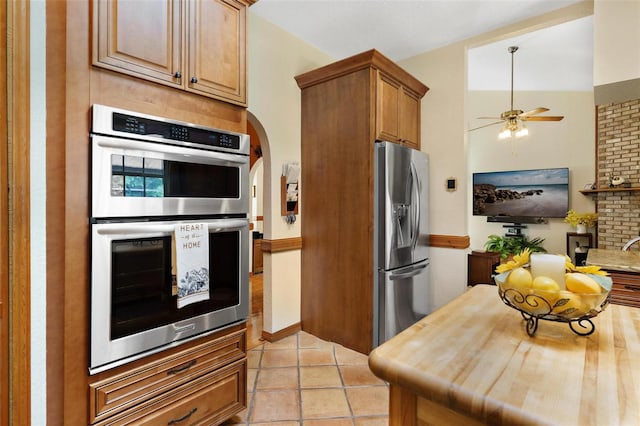 kitchen with wood counters, lofted ceiling, ceiling fan, light tile patterned floors, and stainless steel appliances