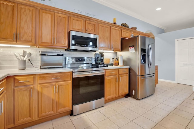 kitchen featuring tasteful backsplash, light tile patterned floors, ornamental molding, and appliances with stainless steel finishes