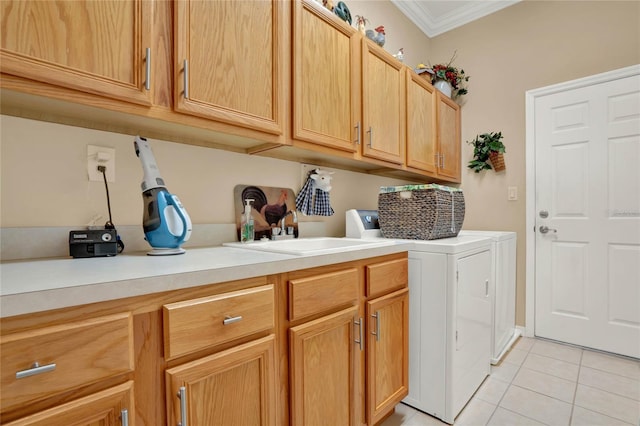 washroom with cabinets, sink, crown molding, light tile patterned floors, and washing machine and clothes dryer