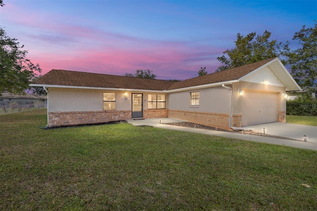 ranch-style house featuring a garage and a yard