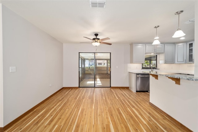 kitchen with gray cabinets, stainless steel dishwasher, a wealth of natural light, and light hardwood / wood-style floors