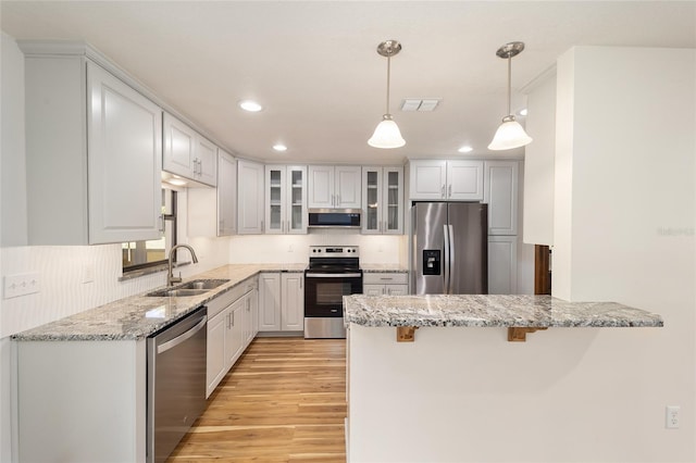 kitchen featuring hanging light fixtures, sink, light wood-type flooring, white cabinetry, and stainless steel appliances