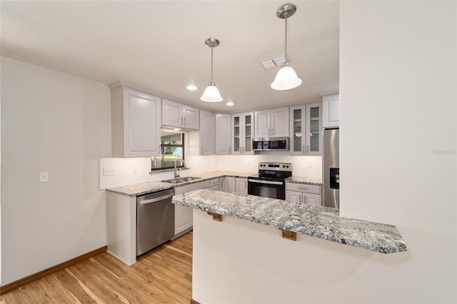 kitchen with kitchen peninsula, light hardwood / wood-style flooring, decorative light fixtures, and appliances with stainless steel finishes