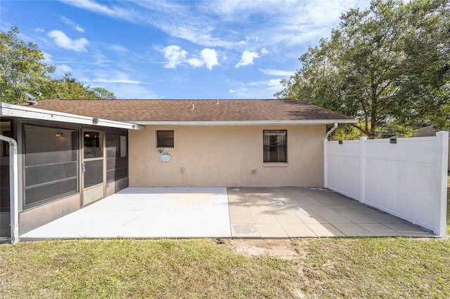 rear view of property featuring a sunroom, a patio area, and a lawn