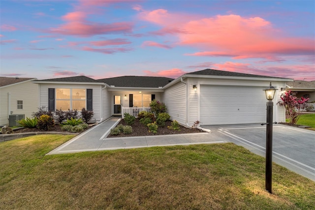 single story home featuring driveway, an attached garage, covered porch, a yard, and central AC