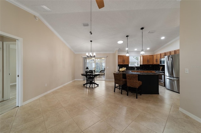 kitchen with a kitchen island, ornamental molding, appliances with stainless steel finishes, dark countertops, and decorative light fixtures