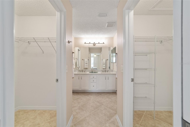 bathroom featuring a sink, a textured ceiling, and double vanity