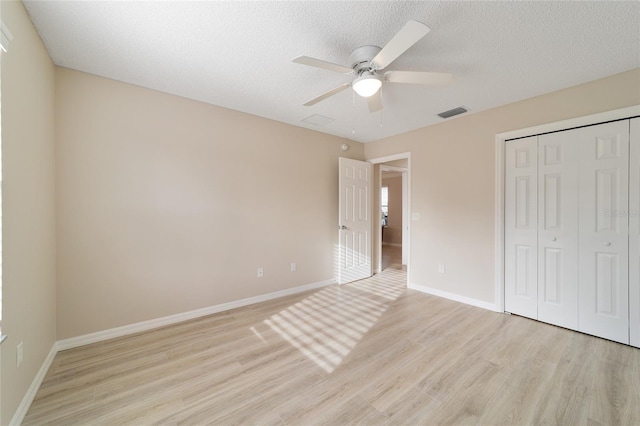 unfurnished bedroom featuring light wood finished floors, a closet, ceiling fan, a textured ceiling, and baseboards