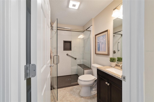 bathroom featuring toilet, a stall shower, vanity, a textured ceiling, and tile patterned floors