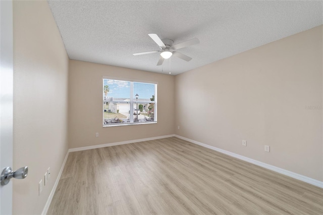 empty room with light wood-type flooring, a ceiling fan, baseboards, and a textured ceiling