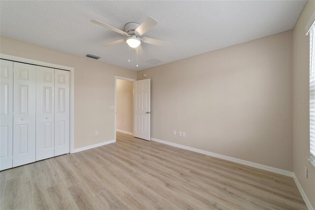 unfurnished bedroom featuring light wood-style floors, a closet, visible vents, and baseboards