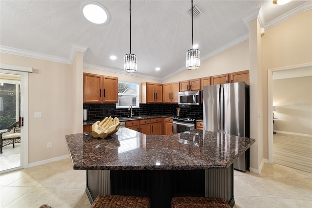 kitchen with appliances with stainless steel finishes, a center island, hanging light fixtures, and light tile patterned floors