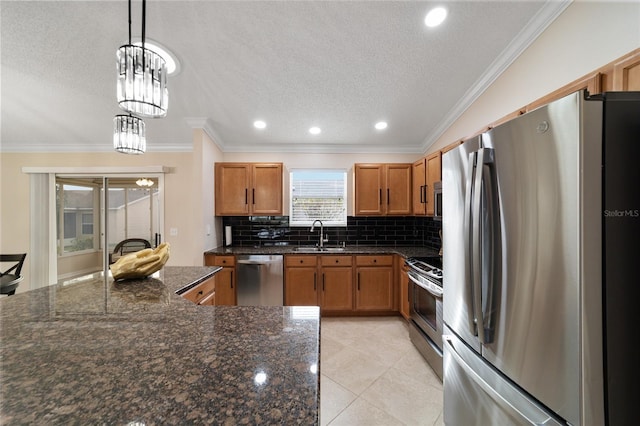 kitchen featuring stainless steel appliances, hanging light fixtures, backsplash, brown cabinets, and dark stone counters