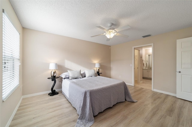 bedroom with visible vents, light wood-style flooring, baseboards, and a textured ceiling