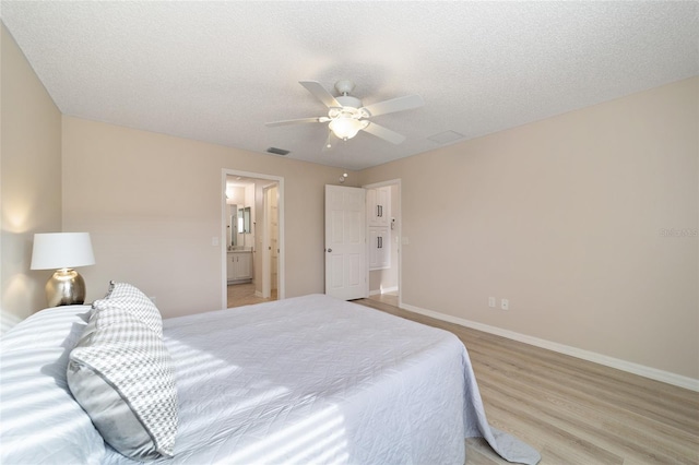 bedroom with light wood-style flooring, a textured ceiling, visible vents, and baseboards