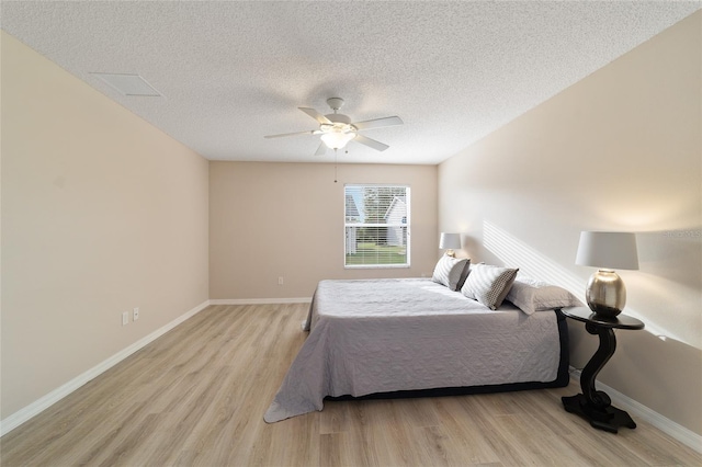 bedroom with light wood-style floors, ceiling fan, a textured ceiling, and baseboards