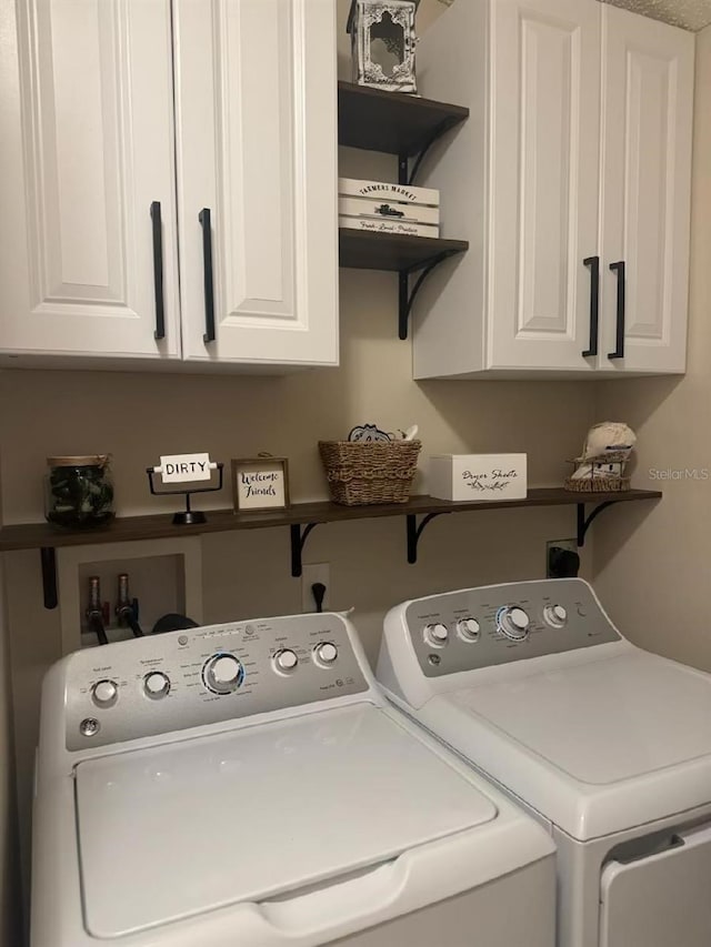 clothes washing area with washing machine and clothes dryer and cabinet space