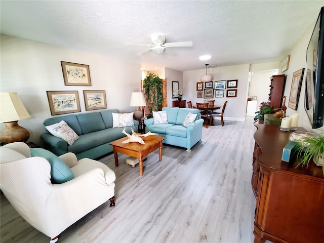 living room with a textured ceiling, light hardwood / wood-style flooring, and ceiling fan