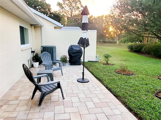 patio terrace at dusk featuring central AC unit and a lawn