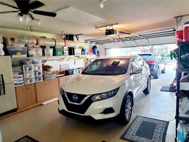 garage featuring white fridge and a garage door opener