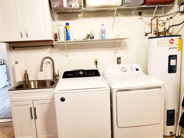 washroom featuring sink, cabinets, water heater, wood-type flooring, and washer and clothes dryer