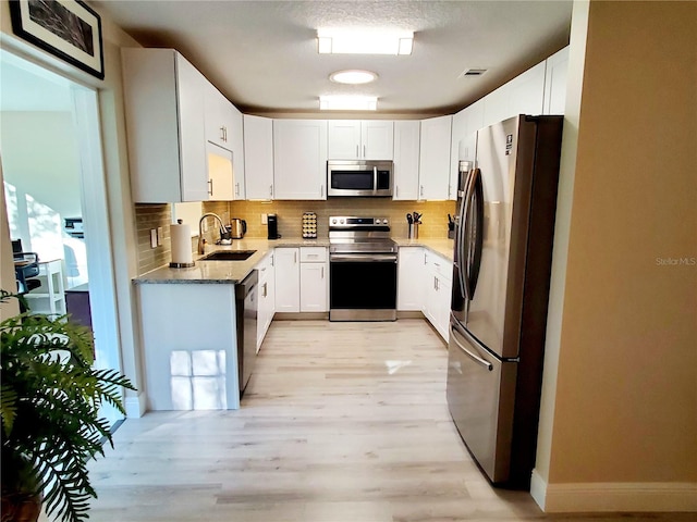 kitchen with light stone countertops, sink, decorative backsplash, white cabinets, and appliances with stainless steel finishes