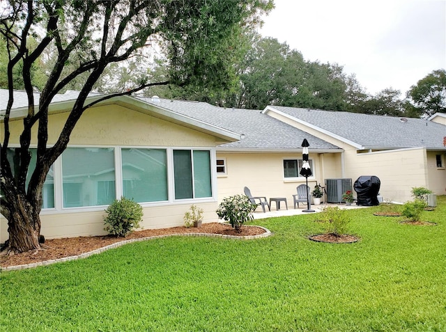 rear view of house featuring a yard, a patio, and central air condition unit