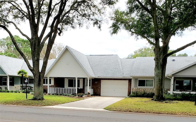 view of front of home featuring covered porch, a garage, and a front lawn