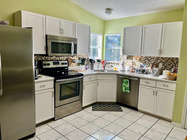 kitchen with appliances with stainless steel finishes, a textured ceiling, white cabinetry, and backsplash