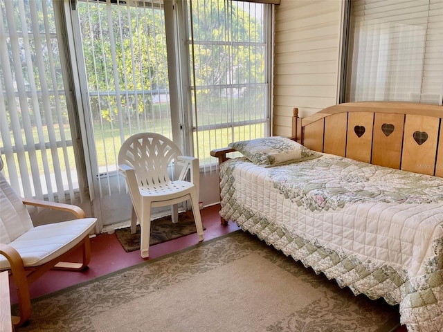 bedroom featuring multiple windows, wooden walls, and carpet floors