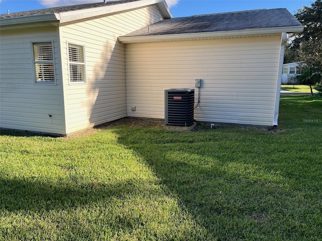 view of property exterior with a lawn and central air condition unit