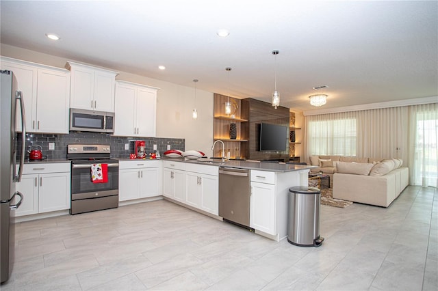 kitchen with kitchen peninsula, appliances with stainless steel finishes, decorative light fixtures, and white cabinetry