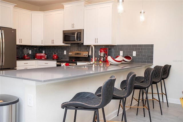 kitchen with a kitchen breakfast bar, kitchen peninsula, white cabinets, and appliances with stainless steel finishes