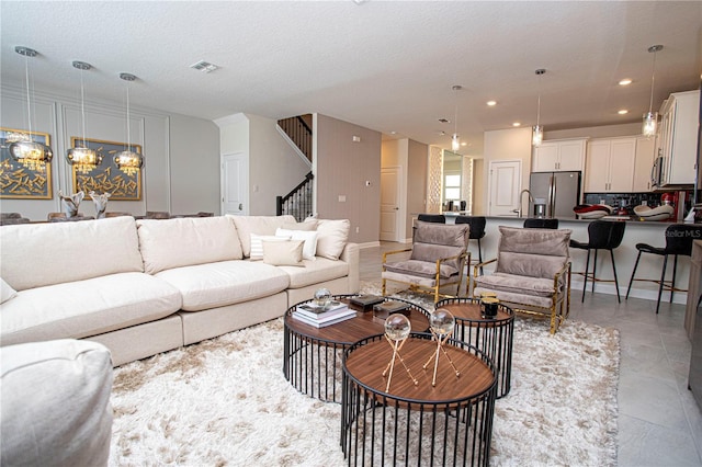 living room featuring a textured ceiling, a notable chandelier, and sink