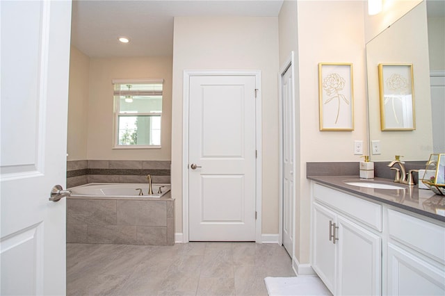 bathroom featuring vanity and tiled tub