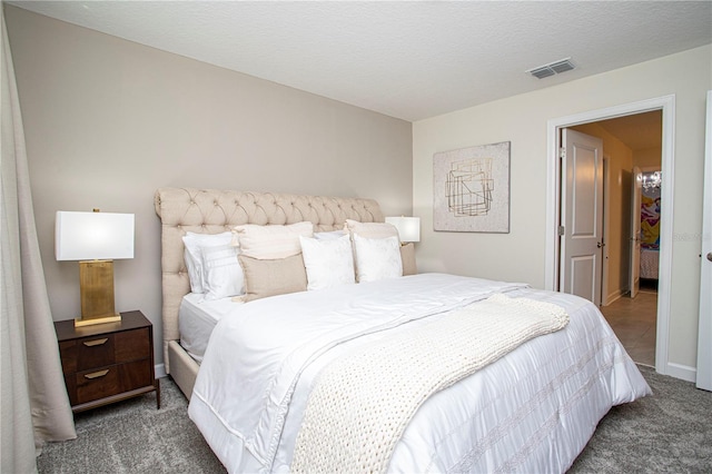 bedroom featuring a textured ceiling and dark carpet