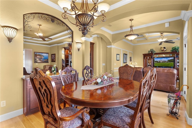 dining room with a raised ceiling, light hardwood / wood-style flooring, ceiling fan with notable chandelier, and ornamental molding