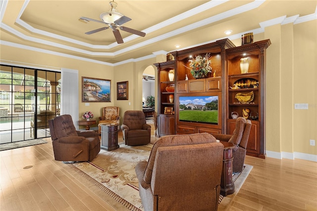 living room with light hardwood / wood-style floors, a raised ceiling, ceiling fan, and crown molding