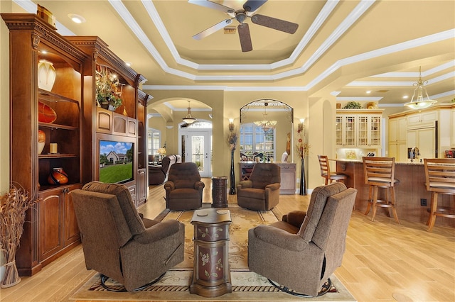 living room with french doors, ceiling fan with notable chandelier, a raised ceiling, crown molding, and light hardwood / wood-style flooring