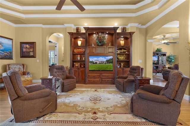 living room with a raised ceiling, crown molding, light hardwood / wood-style flooring, and ceiling fan