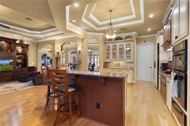 kitchen featuring pendant lighting, stone countertops, light wood-type flooring, and a breakfast bar