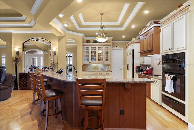 kitchen featuring tasteful backsplash, a kitchen island with sink, and light stone counters