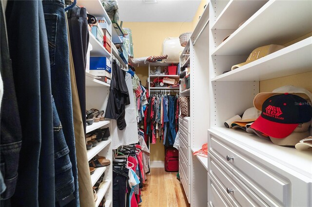 walk in closet with light hardwood / wood-style floors