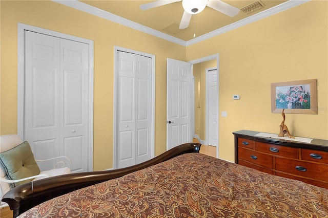 bedroom featuring ceiling fan, crown molding, two closets, and hardwood / wood-style flooring