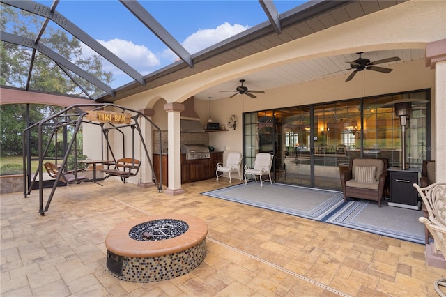 view of patio featuring a fire pit, ceiling fan, area for grilling, and a lanai