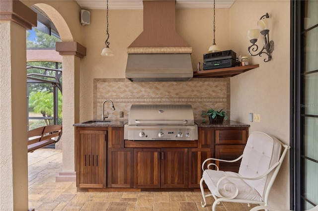 kitchen featuring sink, backsplash, crown molding, pendant lighting, and extractor fan