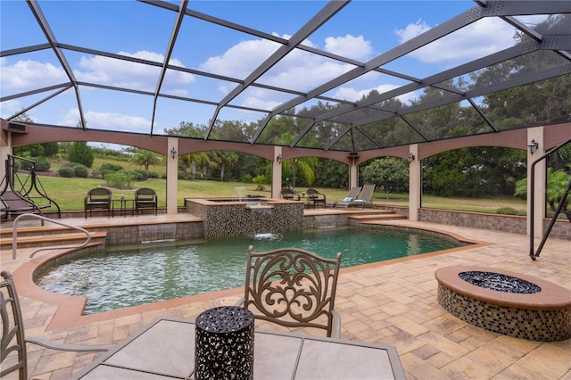 view of swimming pool featuring an in ground hot tub, pool water feature, glass enclosure, a fire pit, and a patio