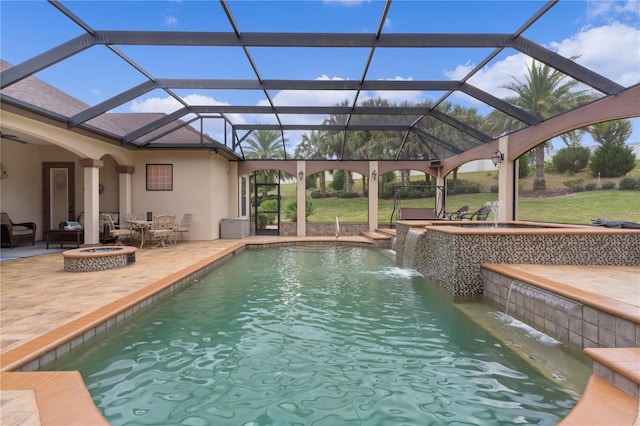 view of pool with a fire pit, glass enclosure, a lawn, pool water feature, and a patio area