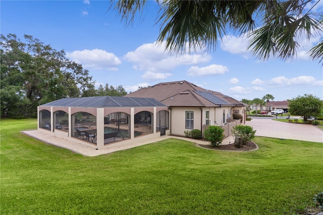 back of house with a lanai and a lawn