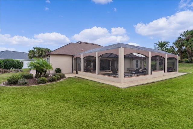 back of property with a lawn, glass enclosure, and a patio